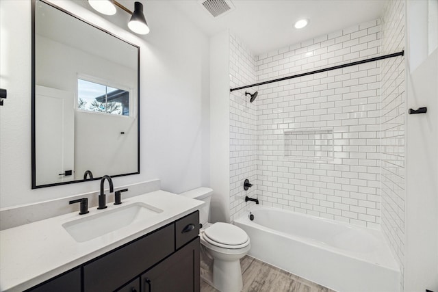 full bathroom featuring hardwood / wood-style flooring, vanity, toilet, and tiled shower / bath combo