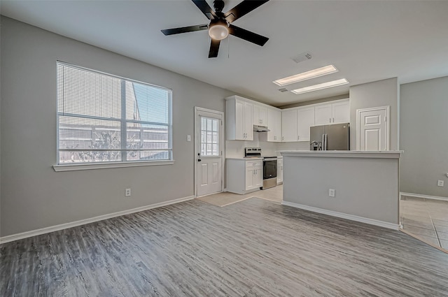 kitchen featuring a kitchen island, light hardwood / wood-style floors, ceiling fan, appliances with stainless steel finishes, and white cabinets