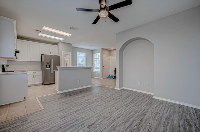 kitchen featuring white cabinets, light hardwood / wood-style flooring, a kitchen island, and stainless steel fridge with ice dispenser