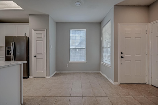 kitchen with white cabinetry, light tile patterned floors, and stainless steel refrigerator with ice dispenser