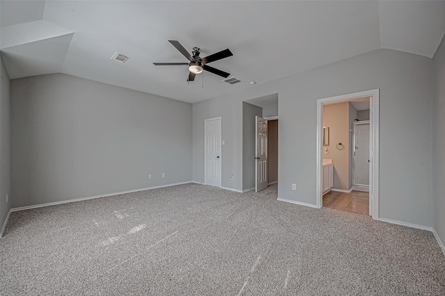 unfurnished bedroom featuring a closet, lofted ceiling, ceiling fan, light carpet, and ensuite bathroom