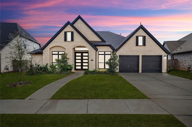 french country home featuring a garage and a lawn