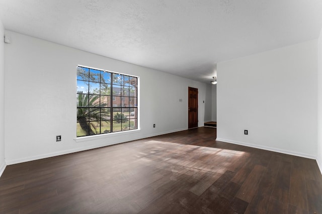 empty room with dark wood-type flooring and a textured ceiling