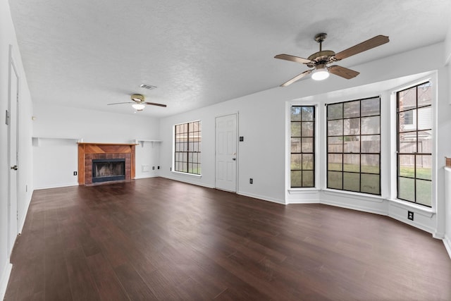 unfurnished living room with dark hardwood / wood-style floors, a wealth of natural light, a textured ceiling, and a fireplace