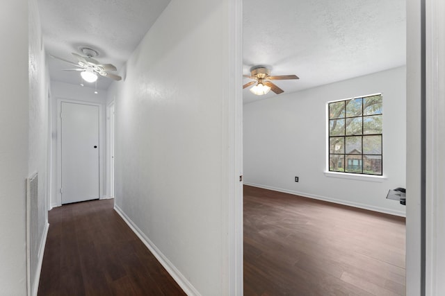 corridor with dark hardwood / wood-style flooring and a textured ceiling