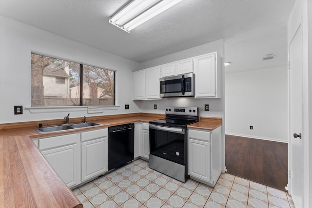 kitchen with stainless steel appliances, sink, a textured ceiling, and white cabinets