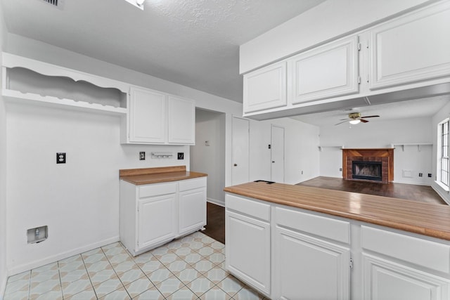 kitchen with white cabinetry, a textured ceiling, and ceiling fan