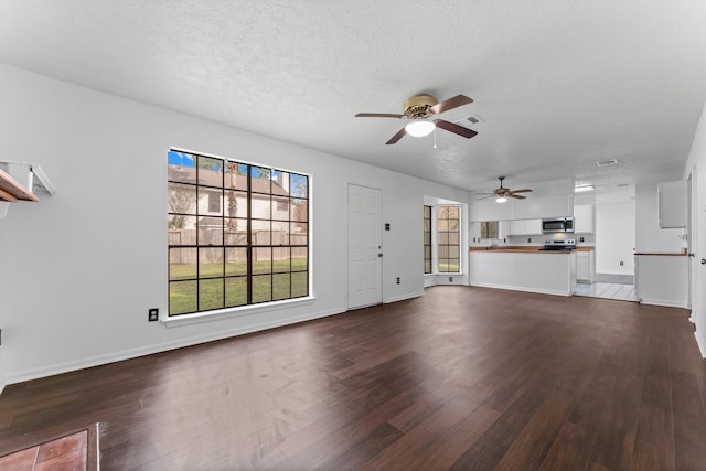 unfurnished living room featuring dark hardwood / wood-style flooring, ceiling fan, a wealth of natural light, and a textured ceiling