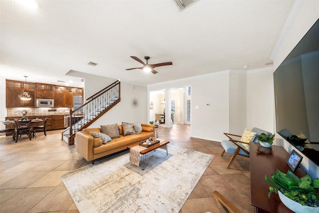 living area with ceiling fan, light tile patterned floors, visible vents, stairs, and crown molding