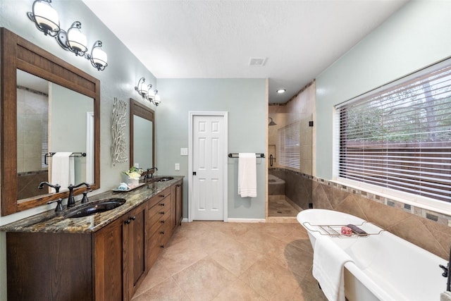 full bath with double vanity, a freestanding tub, a stall shower, and a sink