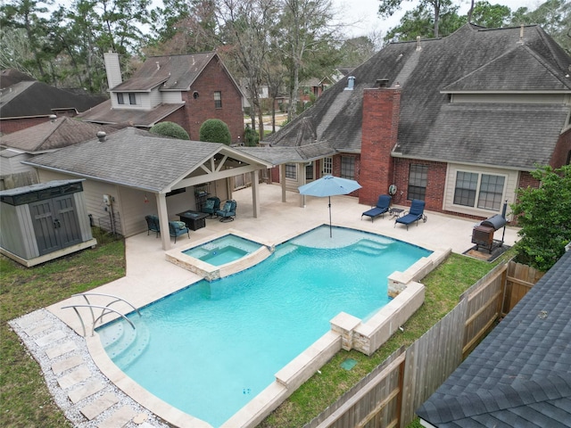 view of pool featuring a patio area, a fenced backyard, and a pool with connected hot tub