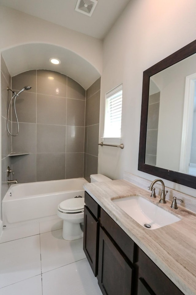 full bathroom with tile patterned flooring, tiled shower / bath, vanity, and toilet