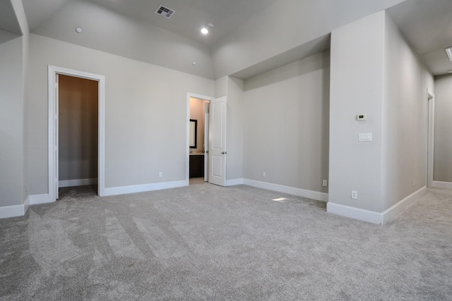 unfurnished bedroom with light carpet, vaulted ceiling, and ensuite bathroom