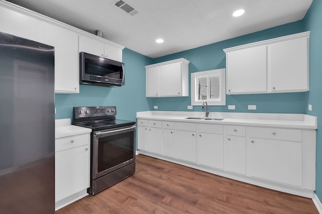 kitchen with sink, appliances with stainless steel finishes, dark hardwood / wood-style floors, a textured ceiling, and white cabinets