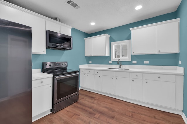 617 4th Ave N, Texas City, TX 77590 - kitchen with stainless steel appliances, recessed lighting, dark wood-style floors, light countertops, and white cabinets