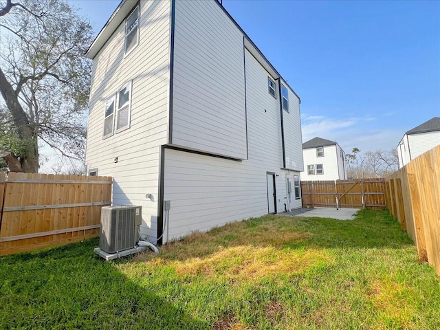 back of house with cooling unit and a lawn