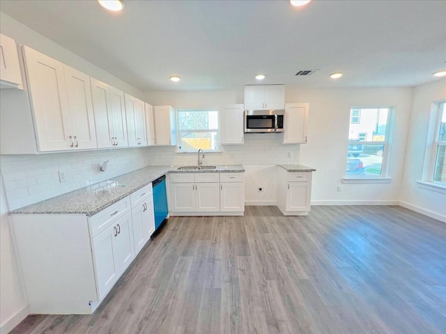 kitchen featuring white cabinetry, black dishwasher, sink, and light wood-type flooring