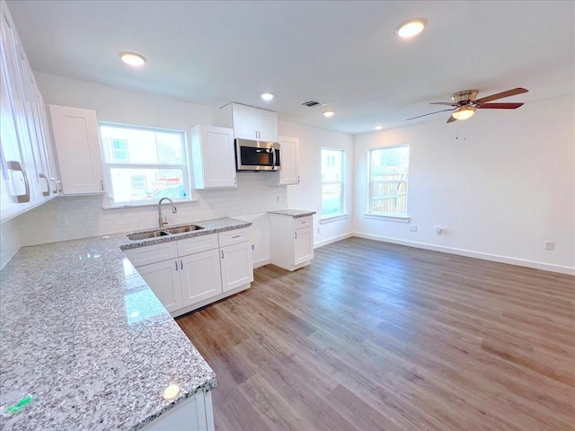 kitchen with white cabinetry, tasteful backsplash, sink, and light stone counters