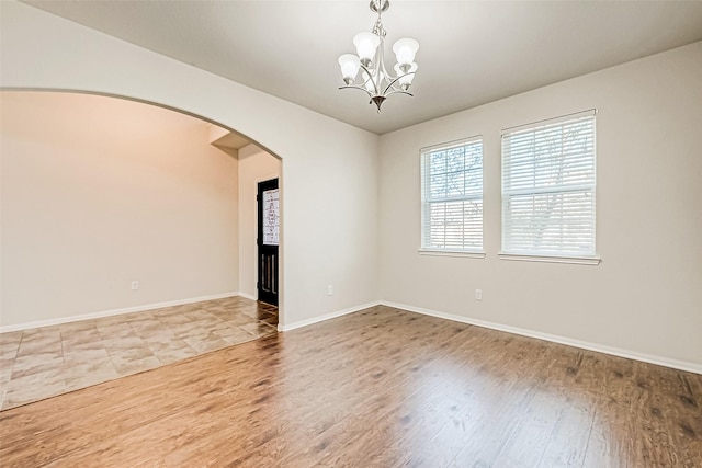 empty room featuring wood-type flooring and a chandelier