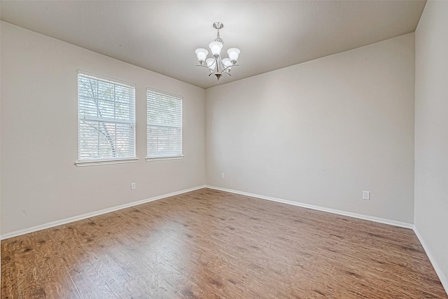 empty room featuring wood-type flooring and a chandelier