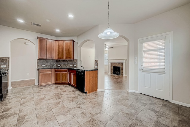 kitchen with pendant lighting, sink, backsplash, a fireplace, and black appliances