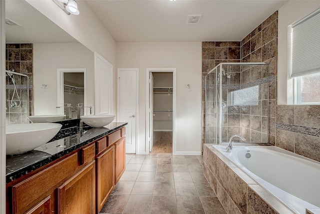 bathroom with tile patterned flooring, vanity, and plus walk in shower