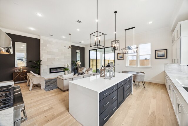 kitchen with white cabinets, ornamental molding, plenty of natural light, and a tile fireplace