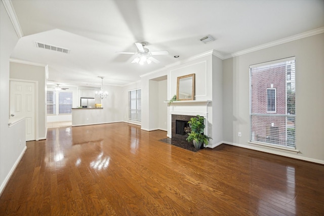 unfurnished living room featuring a tiled fireplace, ornamental molding, wood-type flooring, and ceiling fan with notable chandelier