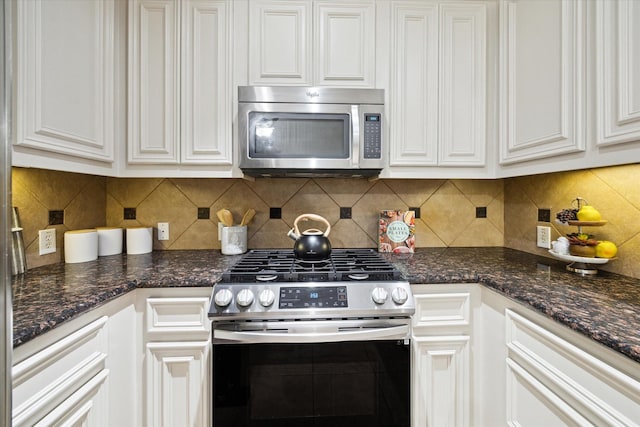 kitchen with white cabinetry, appliances with stainless steel finishes, tasteful backsplash, and dark stone countertops