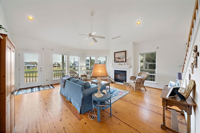 living room featuring a tile fireplace, high vaulted ceiling, ceiling fan, and light hardwood / wood-style floors