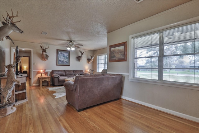 living room with ceiling fan, a textured ceiling, and light wood-type flooring