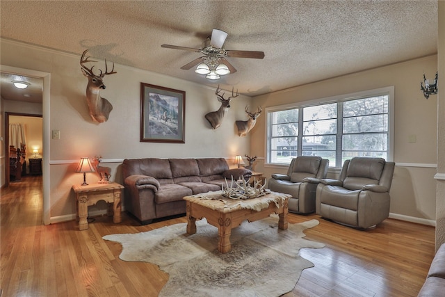 living room featuring ceiling fan, a textured ceiling, and light wood-type flooring