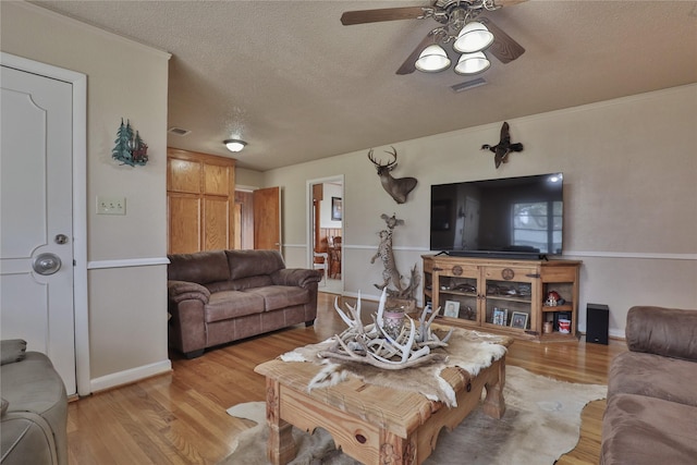 living room with ceiling fan, a textured ceiling, and light wood-type flooring