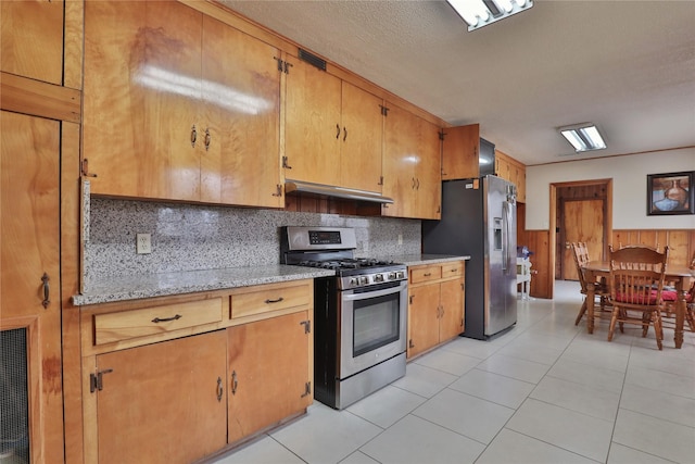 kitchen featuring stainless steel appliances, light tile patterned floors, light stone counters, and decorative backsplash