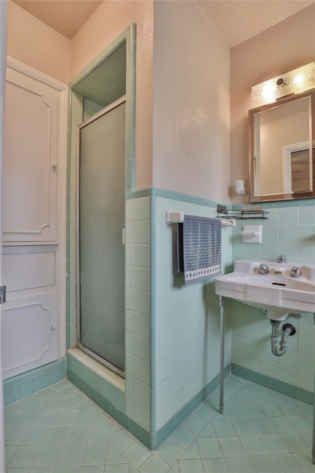 bathroom with sink, tile patterned flooring, a shower with door, and tile walls