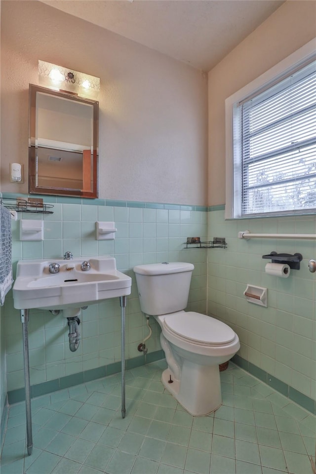 bathroom featuring tile patterned flooring, sink, tile walls, and toilet