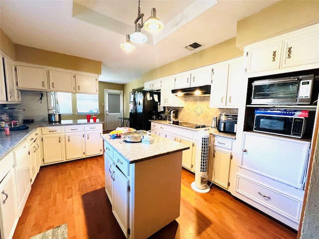 kitchen featuring white cabinetry, a tray ceiling, black appliances, and a center island