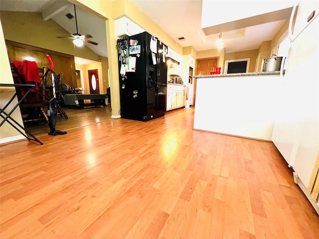 interior space featuring lofted ceiling with beams, white cabinetry, black fridge, and light hardwood / wood-style floors