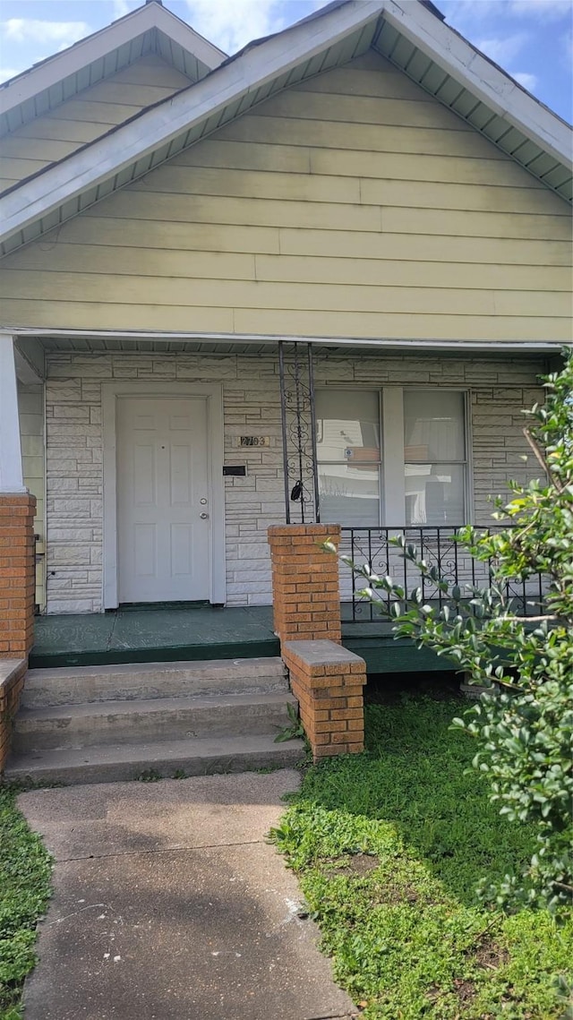 exterior space with a porch and brick siding