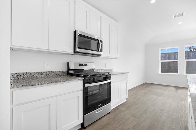 kitchen with light stone counters, appliances with stainless steel finishes, light hardwood / wood-style flooring, and white cabinets