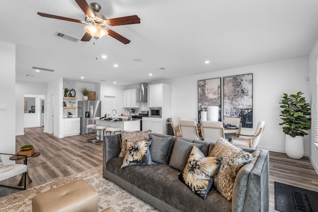 living room with sink, light hardwood / wood-style floors, and ceiling fan