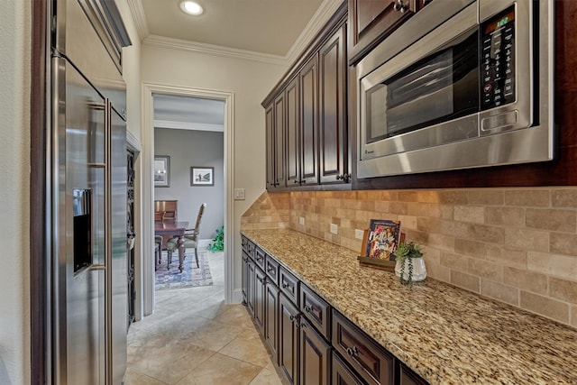 kitchen with light stone countertops, dark brown cabinetry, ornamental molding, and stainless steel appliances