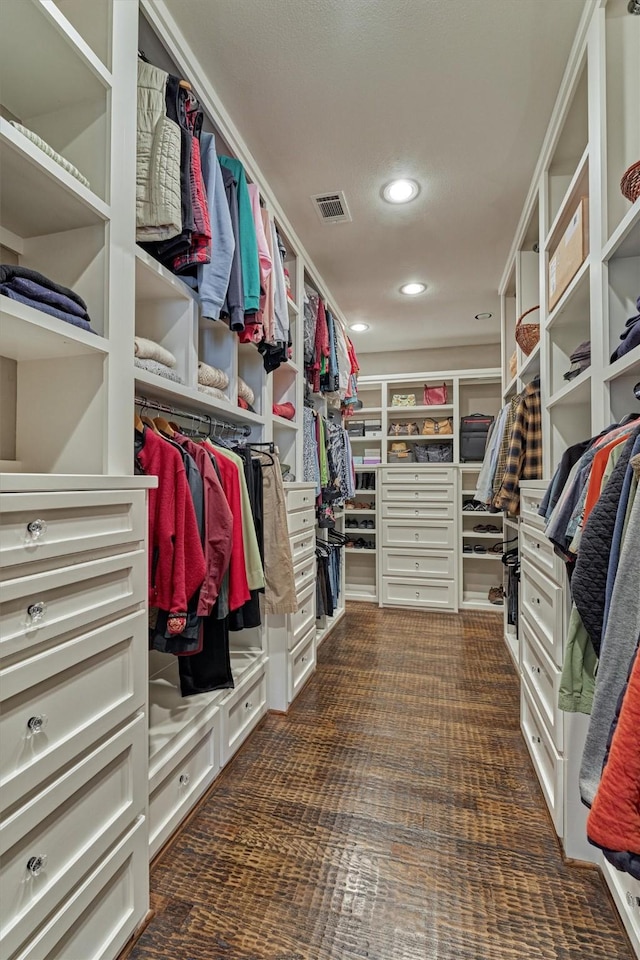 spacious closet featuring visible vents and dark colored carpet