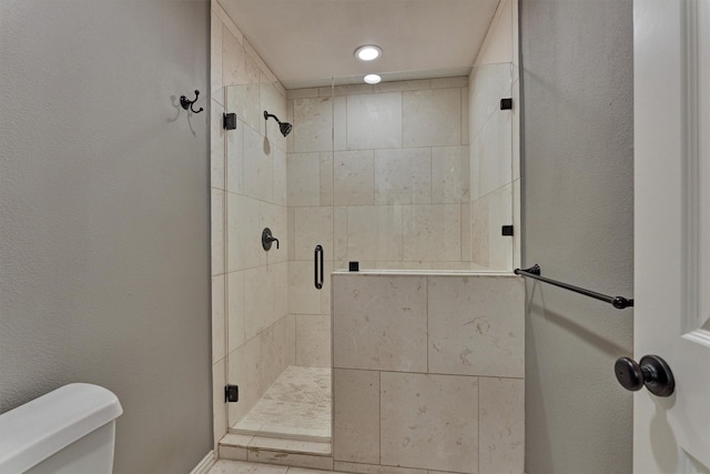 bathroom featuring toilet and a shower stall