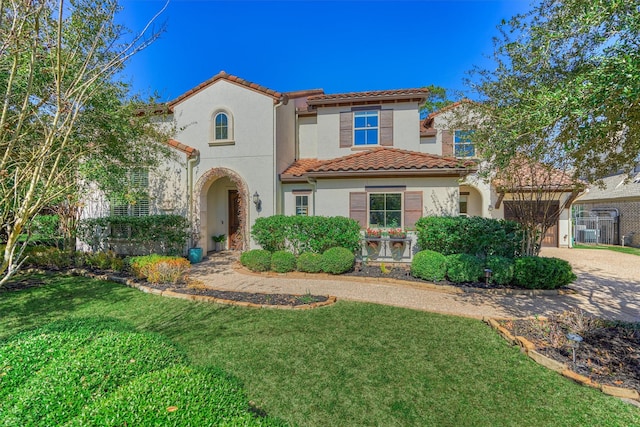 mediterranean / spanish house featuring a tiled roof, a front yard, driveway, and stucco siding