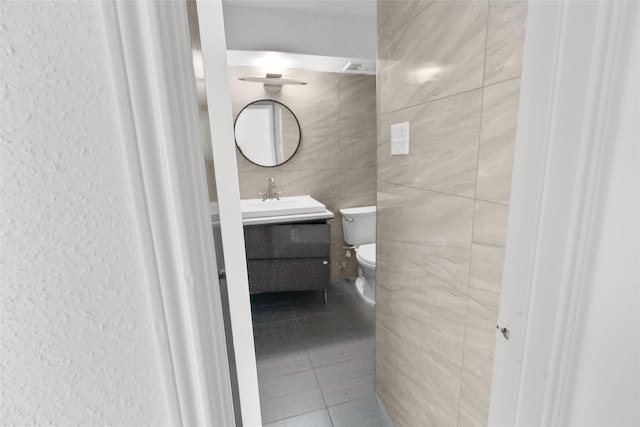 bathroom featuring vanity, toilet, tile patterned flooring, and tile walls