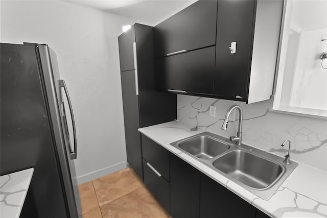 kitchen featuring stainless steel refrigerator, sink, decorative backsplash, light tile patterned floors, and light stone counters