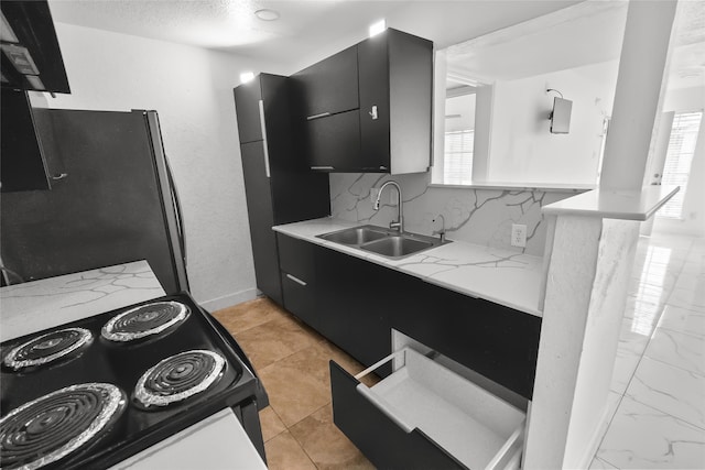 kitchen with sink, stainless steel refrigerator, black range with electric cooktop, decorative backsplash, and kitchen peninsula