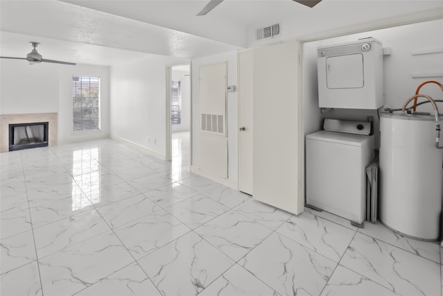 washroom with water heater, stacked washer / drying machine, and ceiling fan