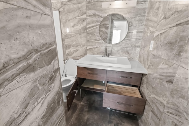 bathroom with vanity, tile walls, and toilet